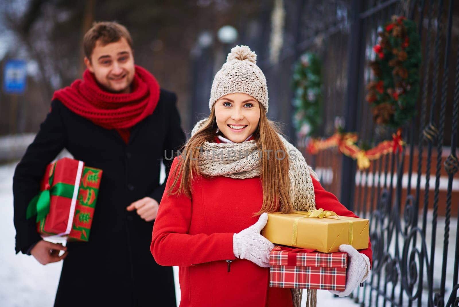 Cute girl with giftboxes looking at camera on background of young man