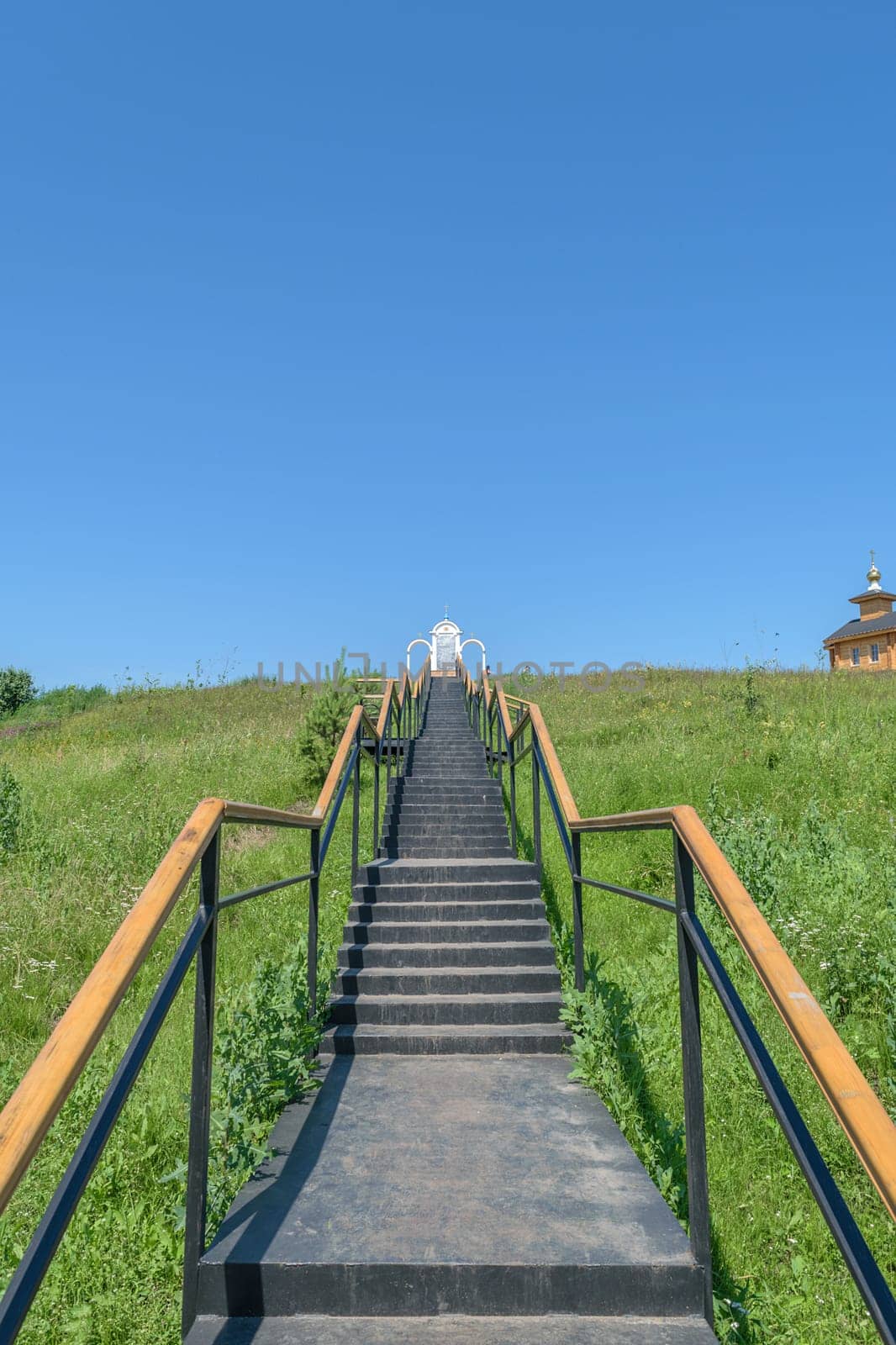 Metal stairs with railings leading up to the place of prayer and a wooden chapel on the hill.