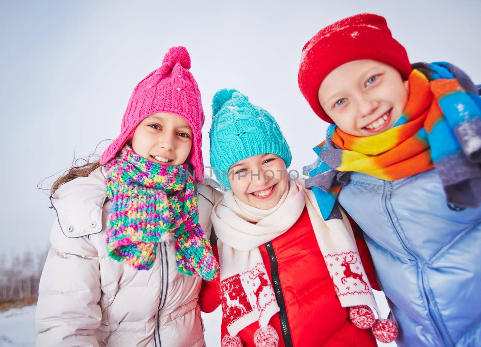 Joyful friends in winterwear looking at camera outdoors