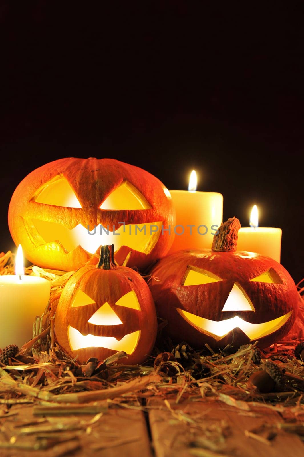 Three illuminated Halloween pumpkins with straw on old weathered wooden boards against a red-brown background in red light