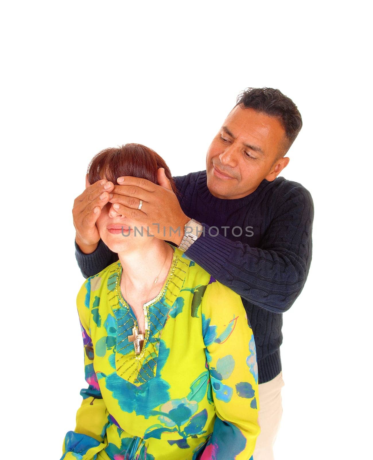 A Hispanic man, standing behind his wife and holding his hands over her.eye's, isolated for white background..