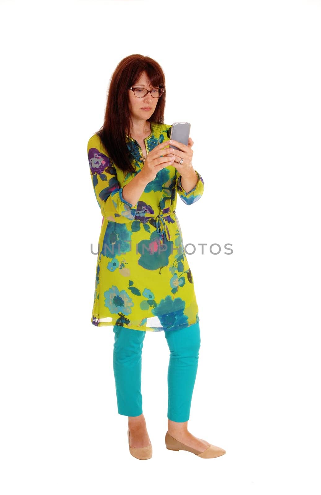 A business woman in a colorful dress dialing on her cell phone, standing.isolated for white background..