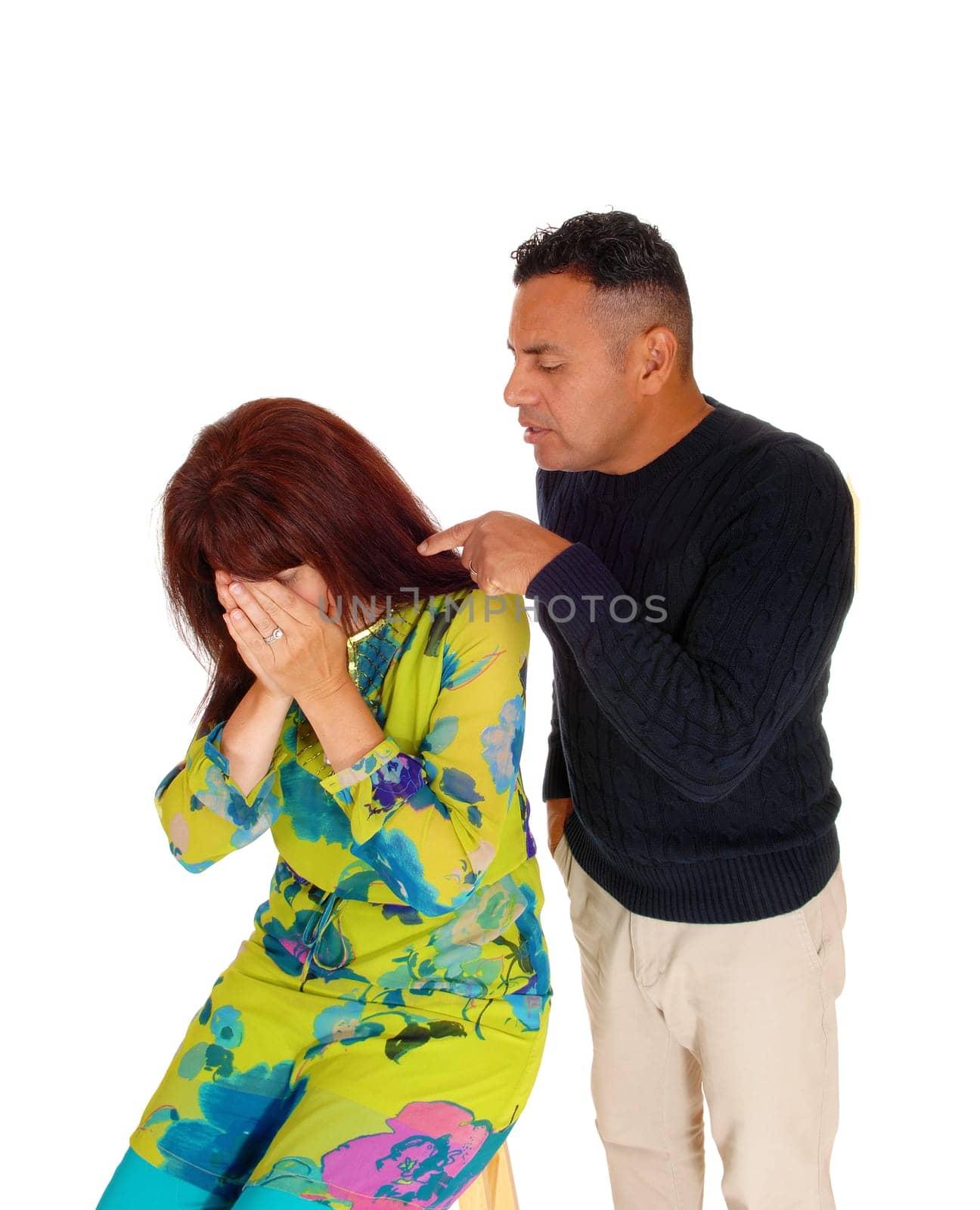 A Hispanic man standing behind his wife and pointing his finger at his.crying wife, domestic violence, isolated for white background. .