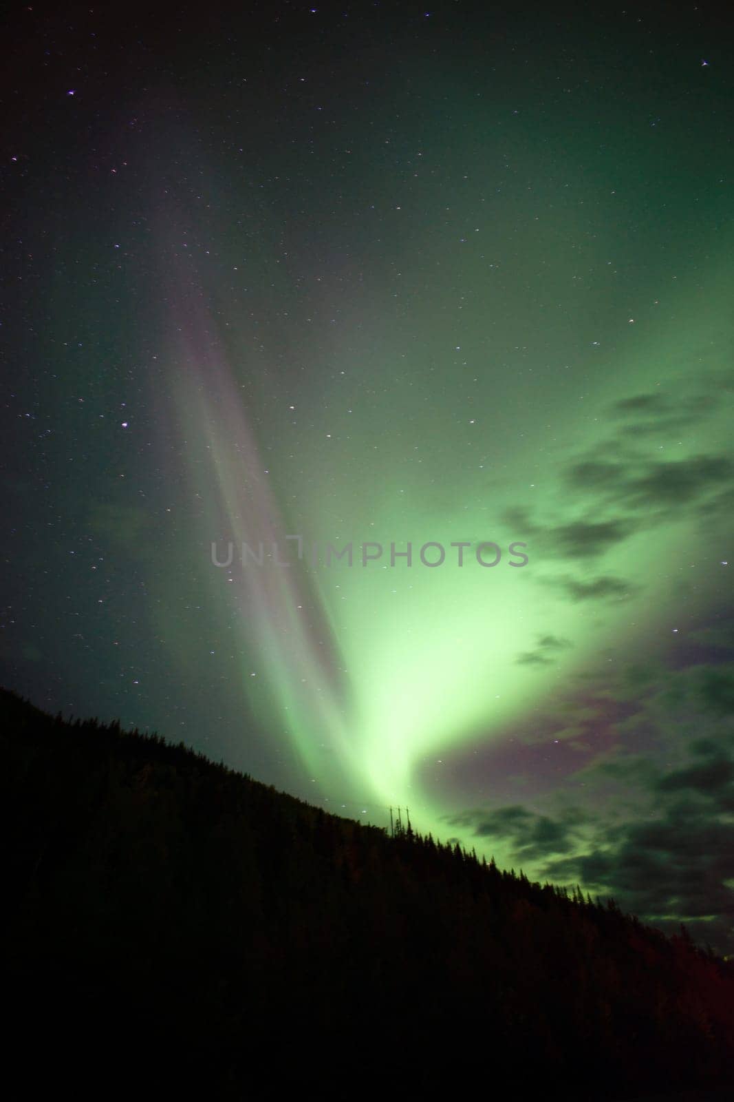 The Northern Lights emerge through the clouds in remote Alaska