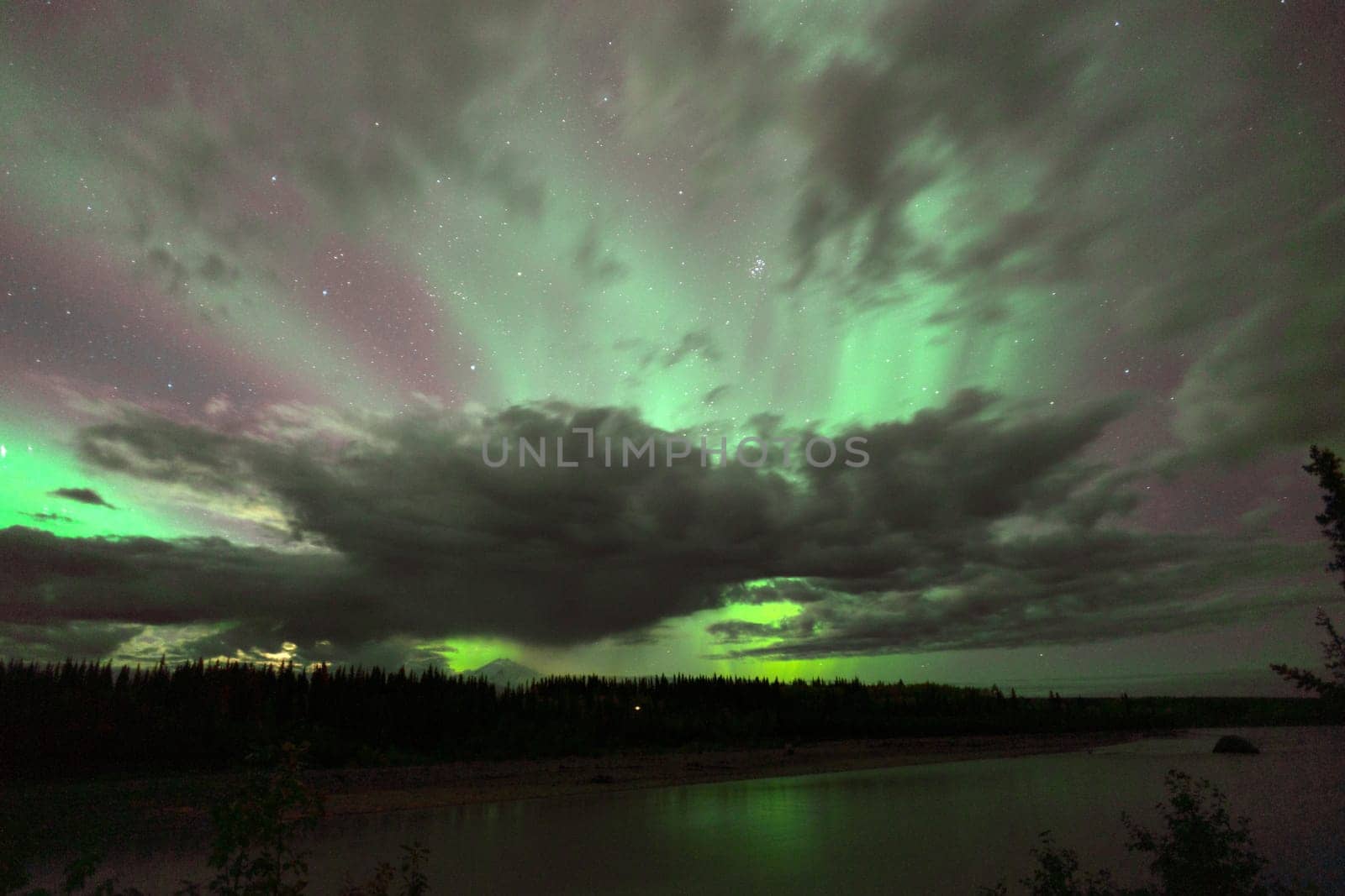 The Northern Lights emerge through the clouds in remote Alaska