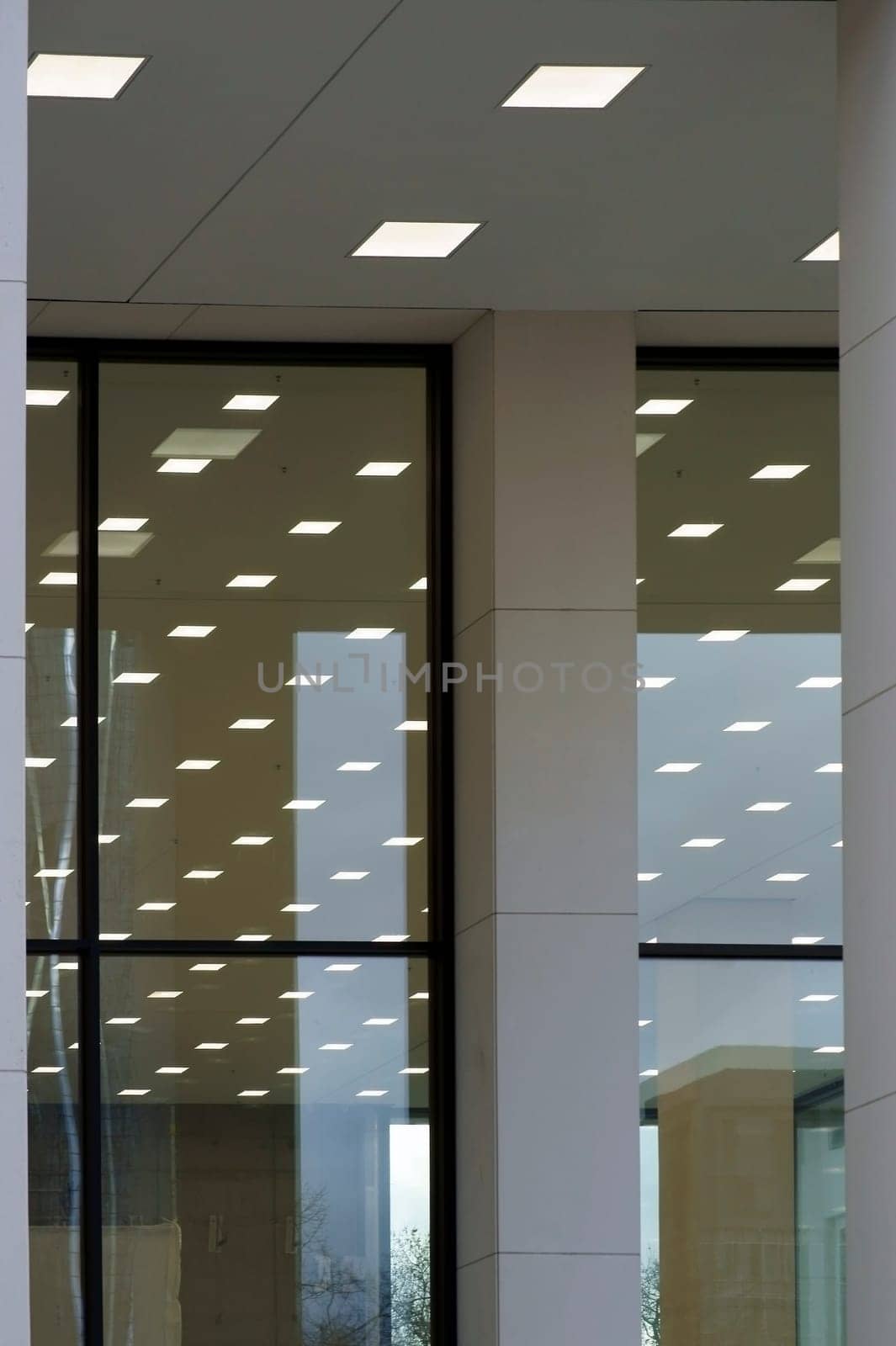 Abstract square ceiling lights are reflected in the glass panes of a panoramic window or shop window.