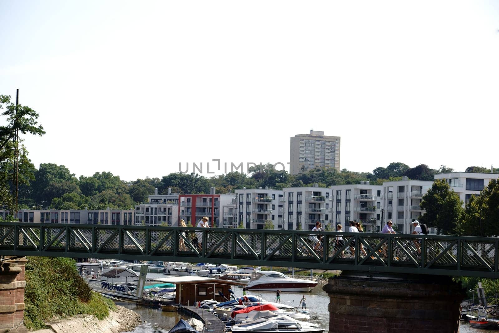 Mainz,Germany – August 22,2015: Pedestrians and cyclists cross a bridge on the Victor-Hugo-Ufer with an inland port and motorboats on August 22,2015 in Mainz.