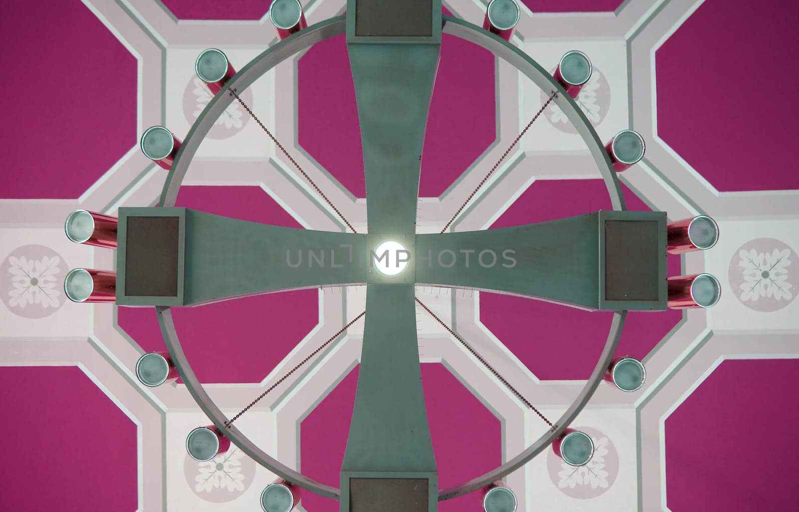 A large round ceiling chandelier with halogen spotlights on a distinctively panelled ceiling.