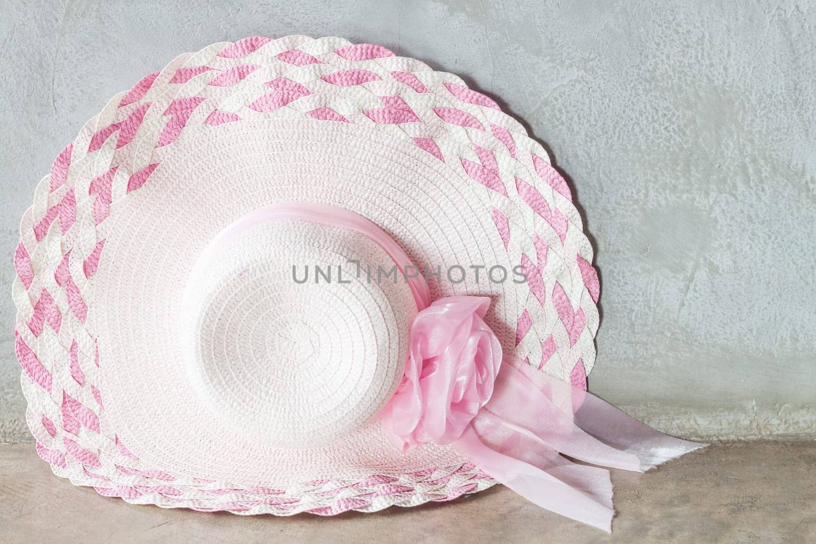Pink hat with ribbon on grey background, stock photo