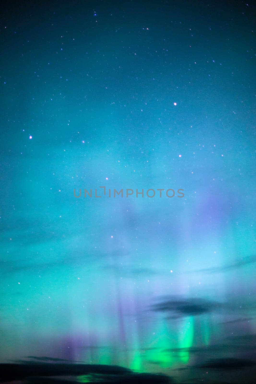 The Northern Lights emerge through the clouds in remote Alaska