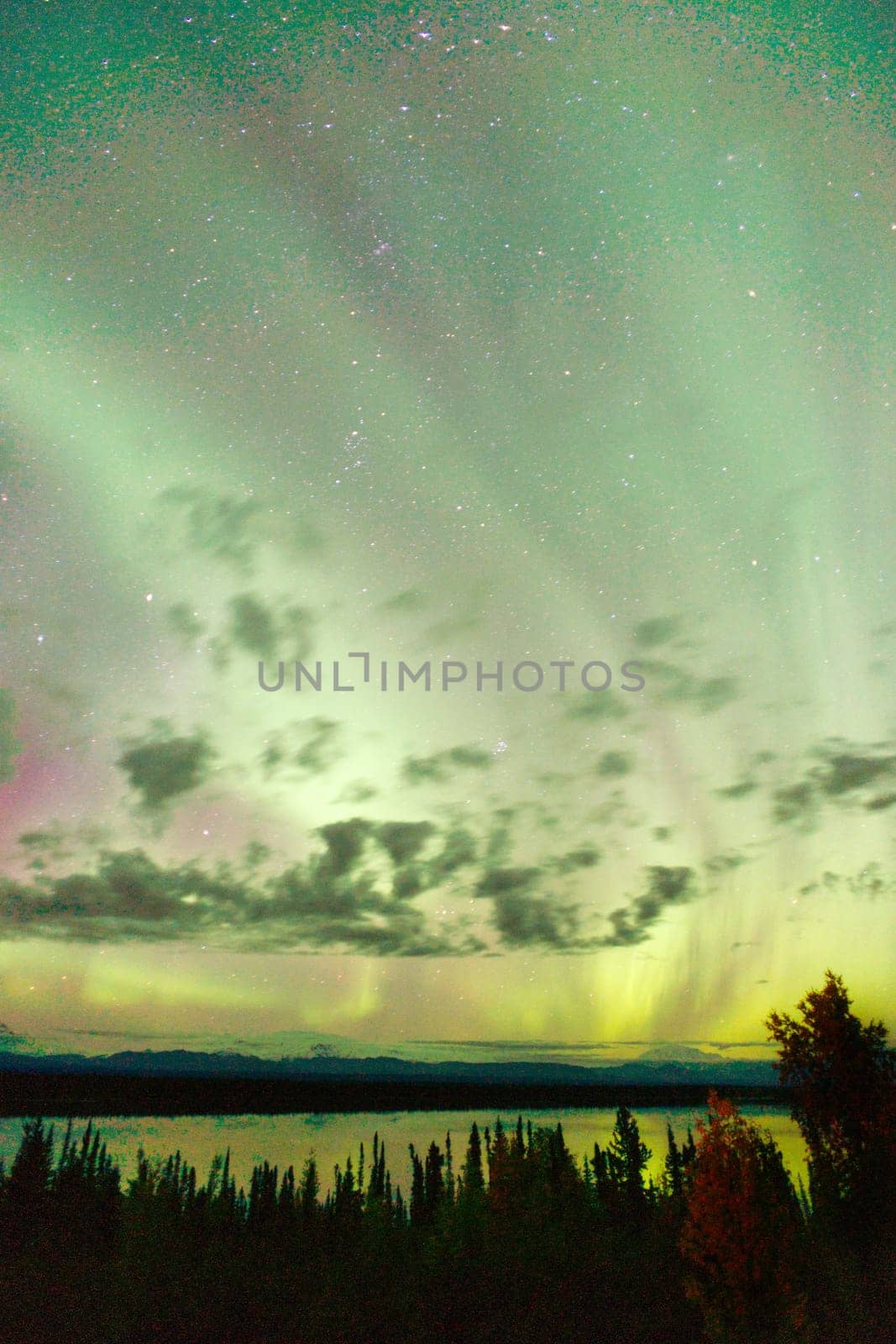 The Northern Lights emerge through the clouds in remote Alaska