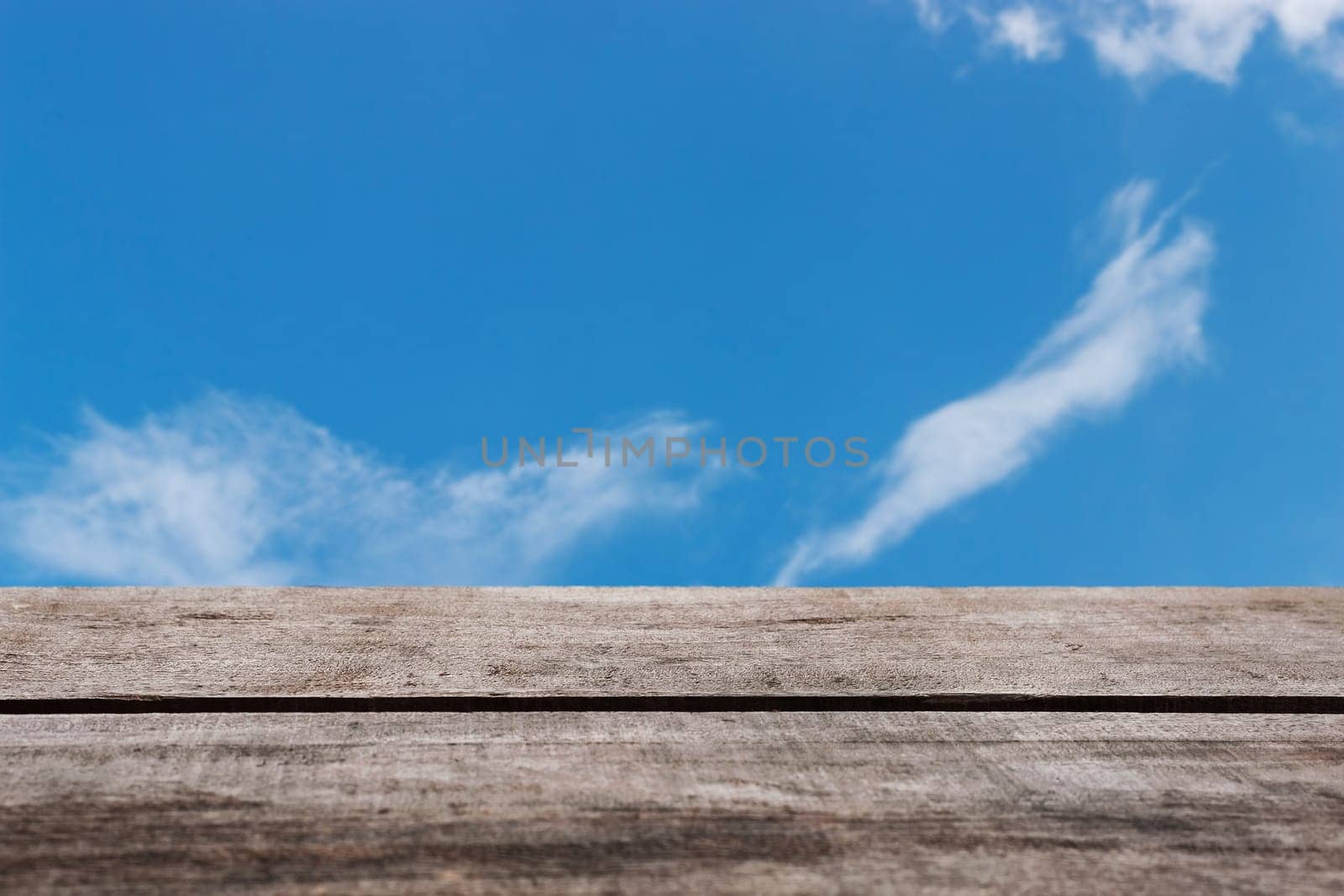 Wooden floor with blue sky and white cloud background