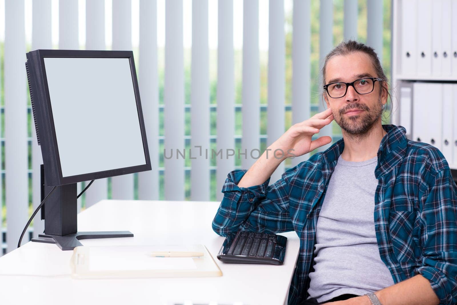 creative man is working in his office and looking in to the camera