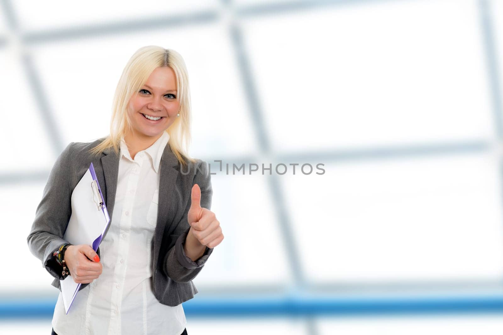 smiling blond young business woman with a clipboard and thumb up