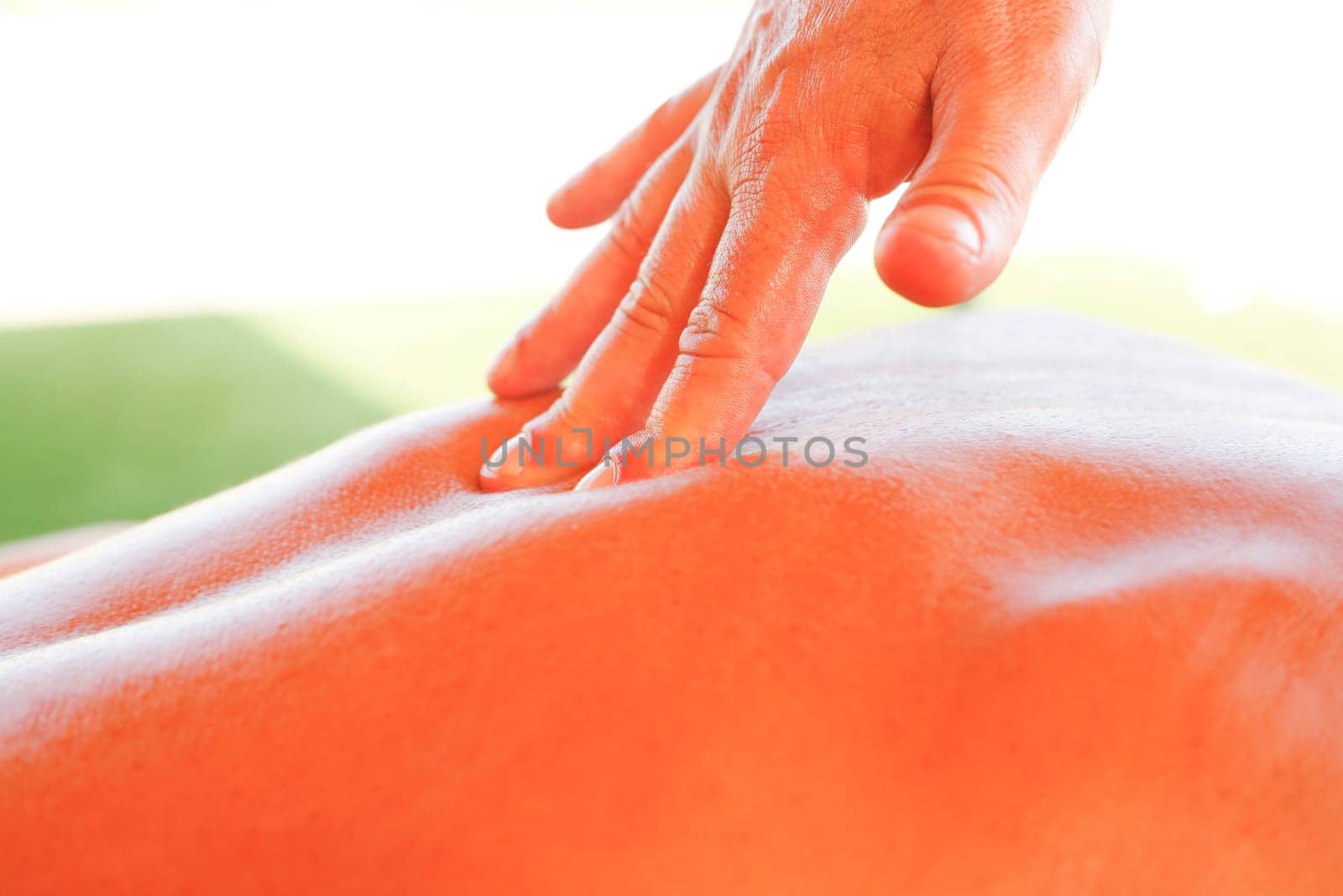 Massage therapist working with suntanned beautiful woman at beach resort