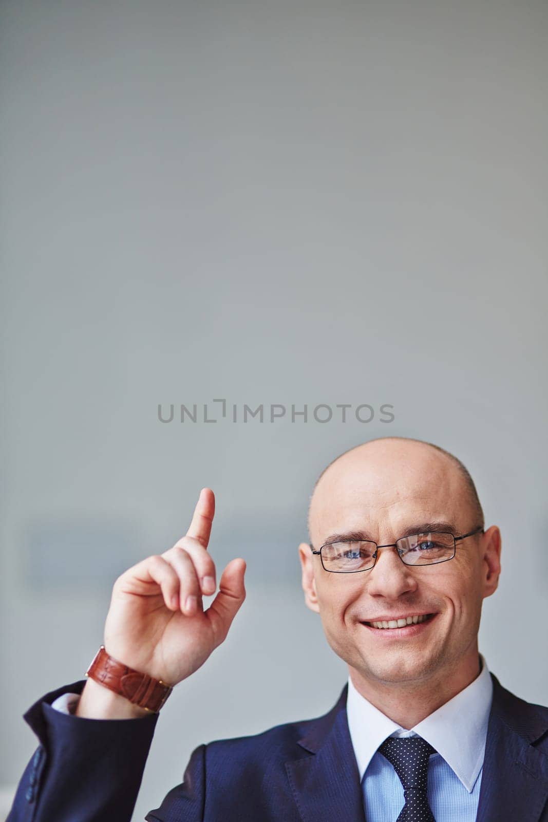 Successful businessman in eyeglasses pointing upwards