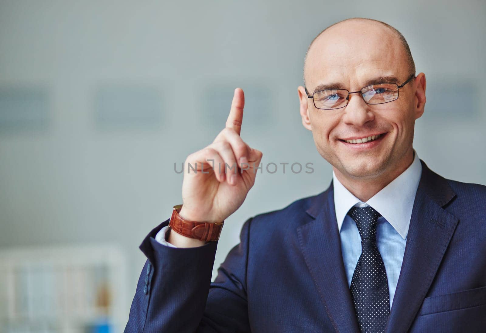 Elegant businessman looking at camera and pointing upwards