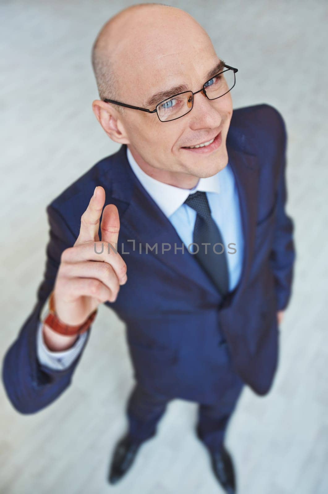 Successful employee in eyeglasses and suit looking at camera with smile