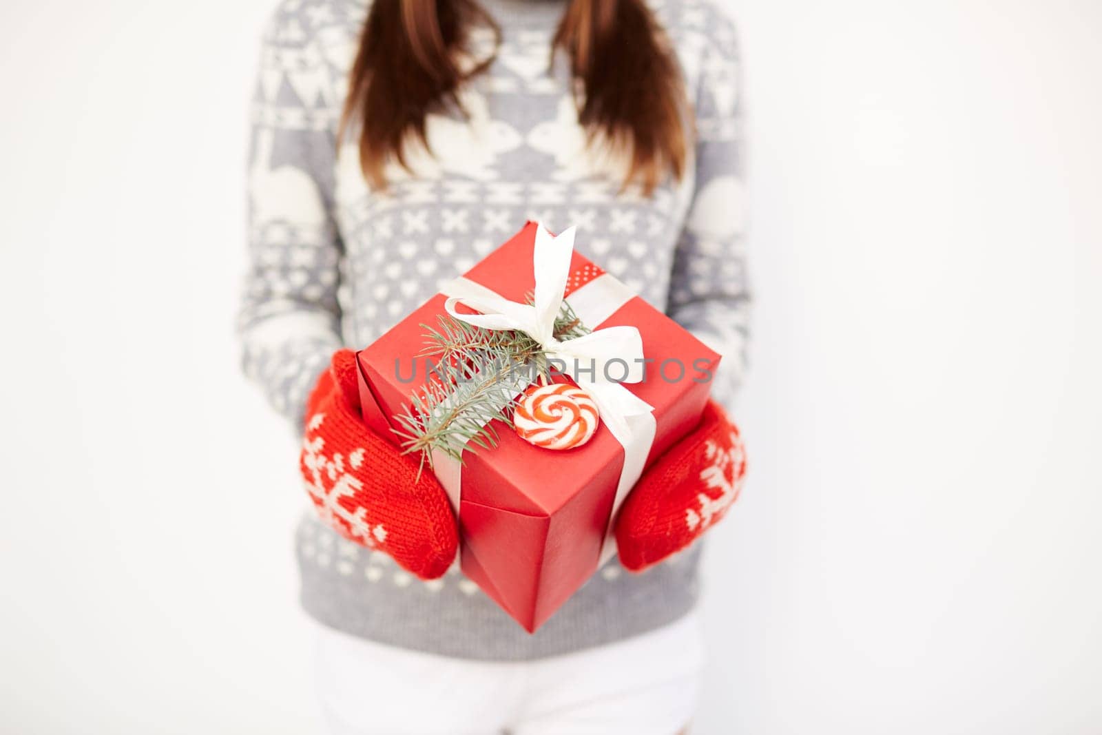 Girl in red knitted mittens holding package with Christmas present