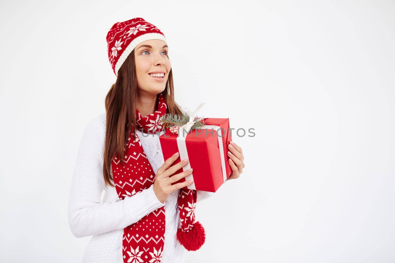 Pretty young female in cap, sweater and scarf holding giftbox