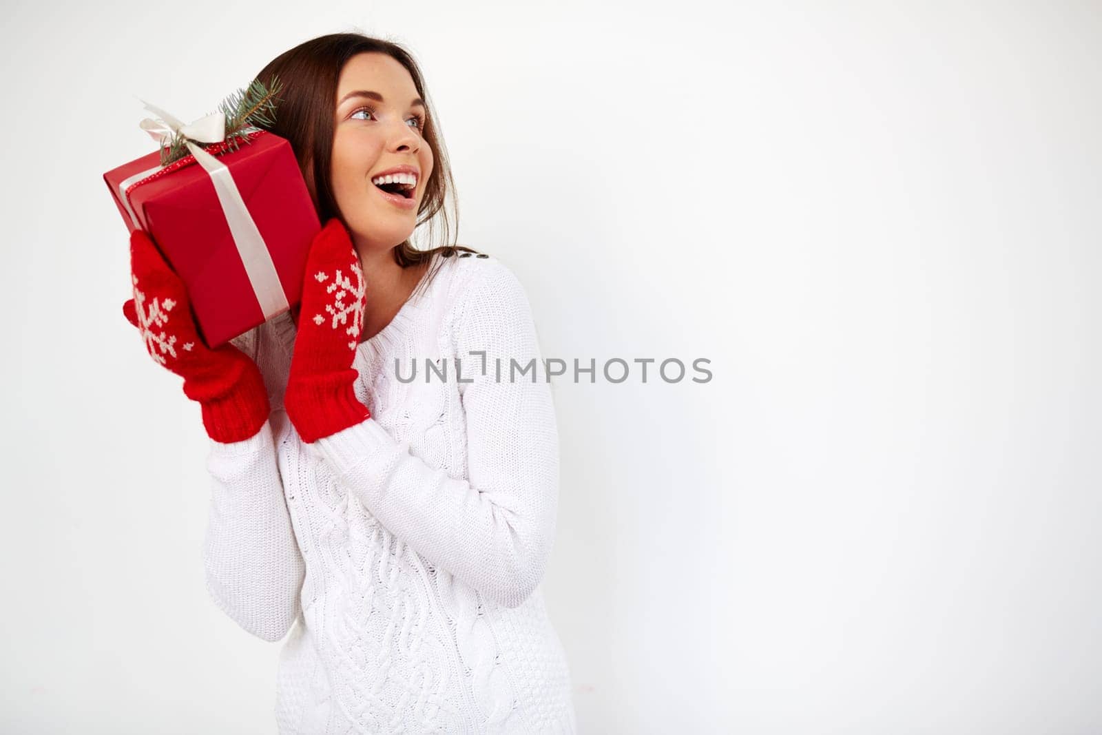 Surprised girl with Christmas gift by her ear