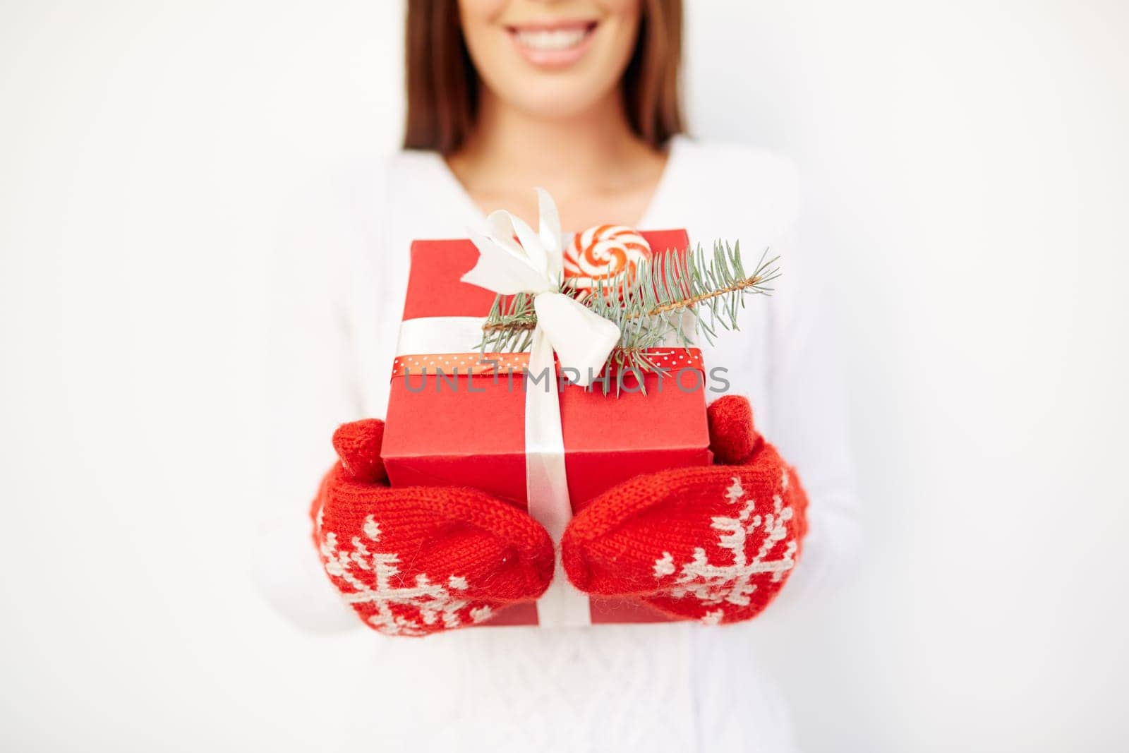 Girl in mittens showing giftbox with Christmas present