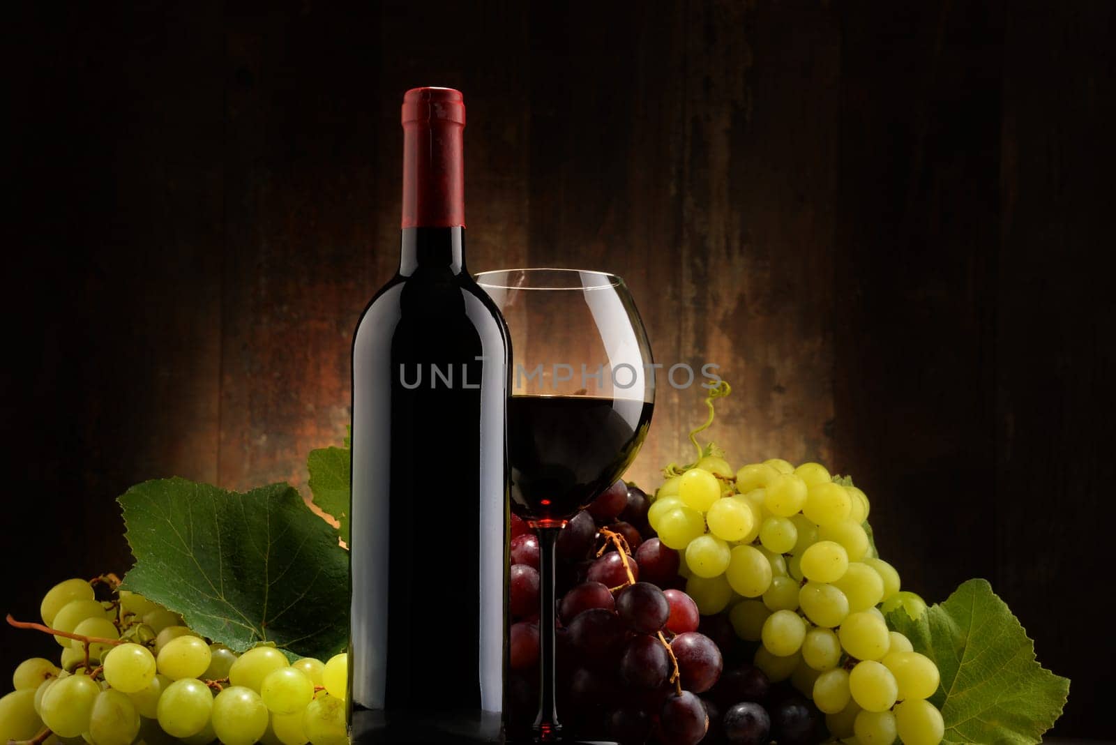 Composition with glass, bottle of red wine and fresh grapes