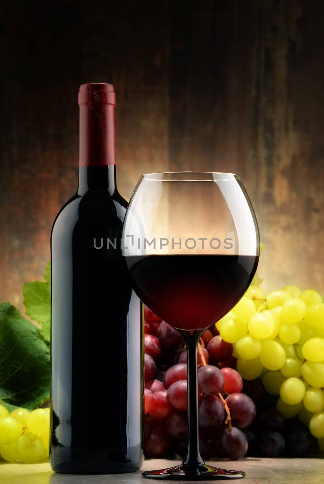 Composition with glass, bottle of red wine and fresh grapes