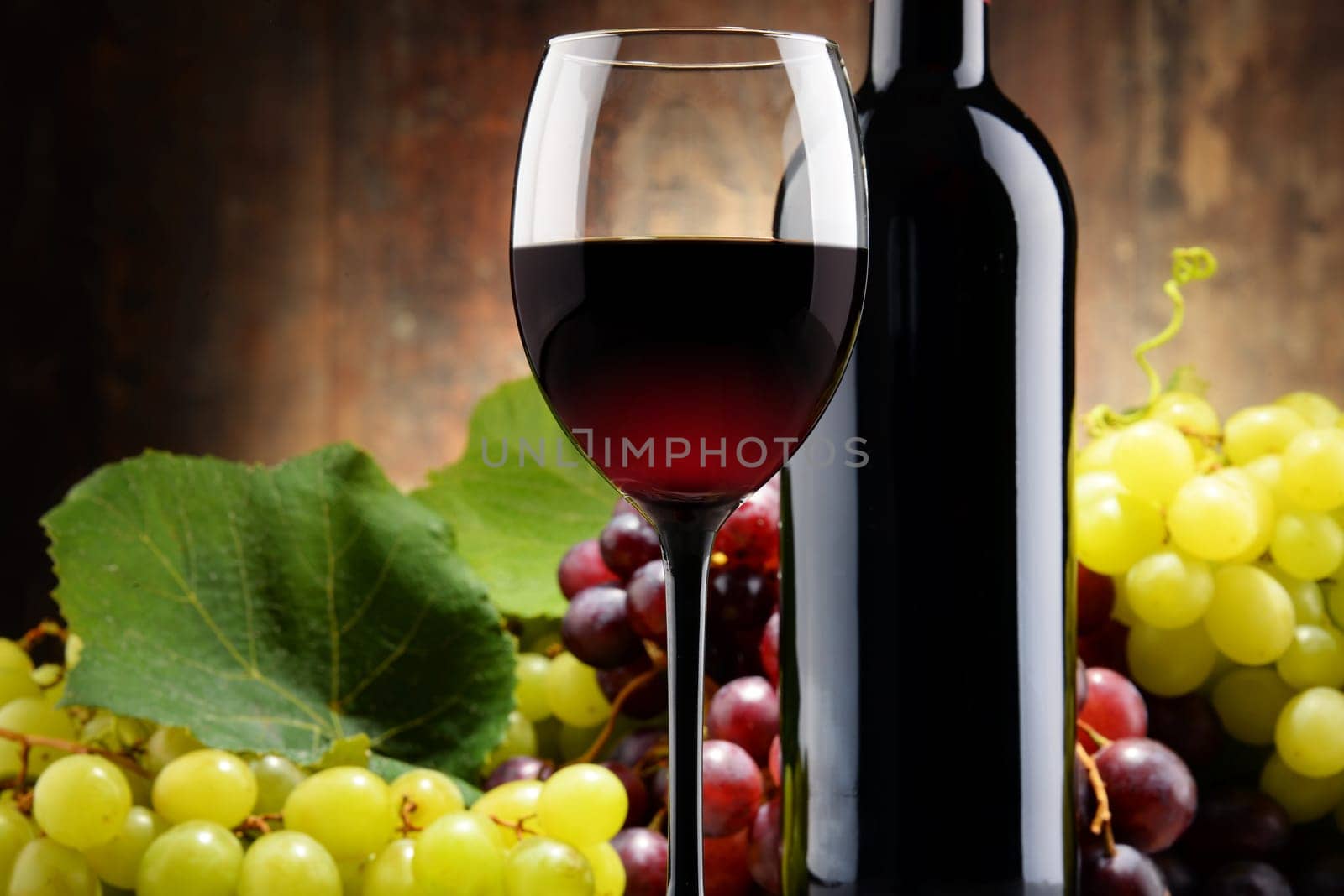Composition with glass, bottle of red wine and fresh grapes.