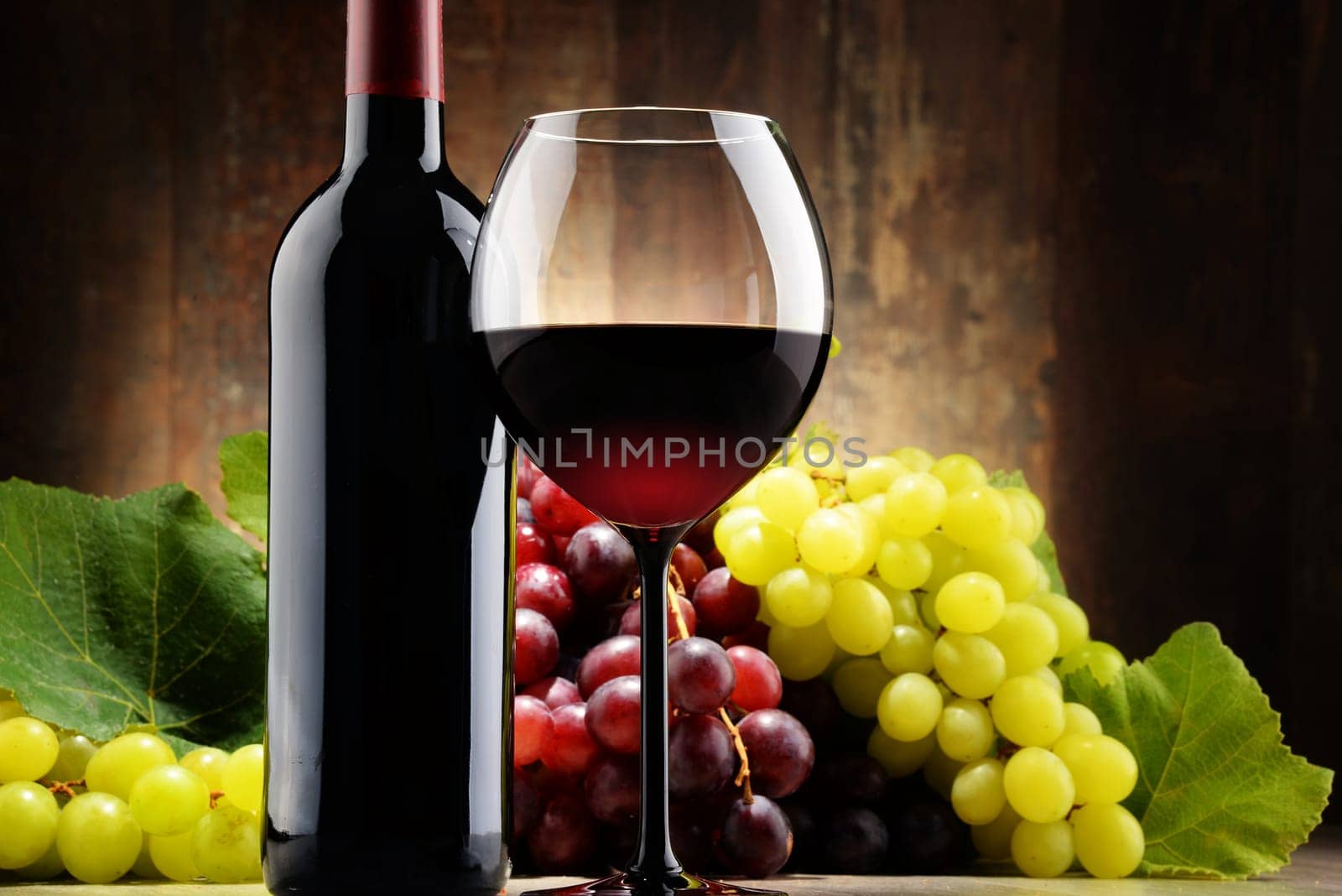Composition with glass, bottle of red wine and fresh grapes