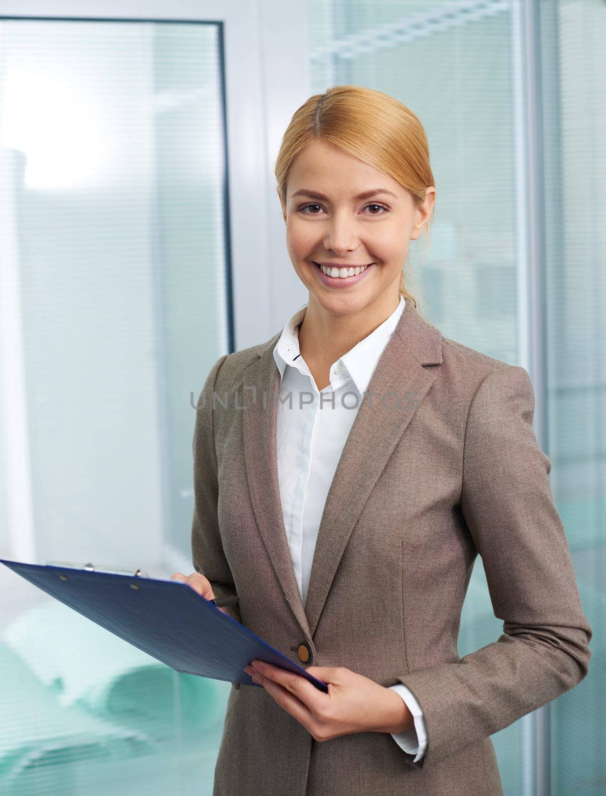 Happy secretary with clipboard looking at camera