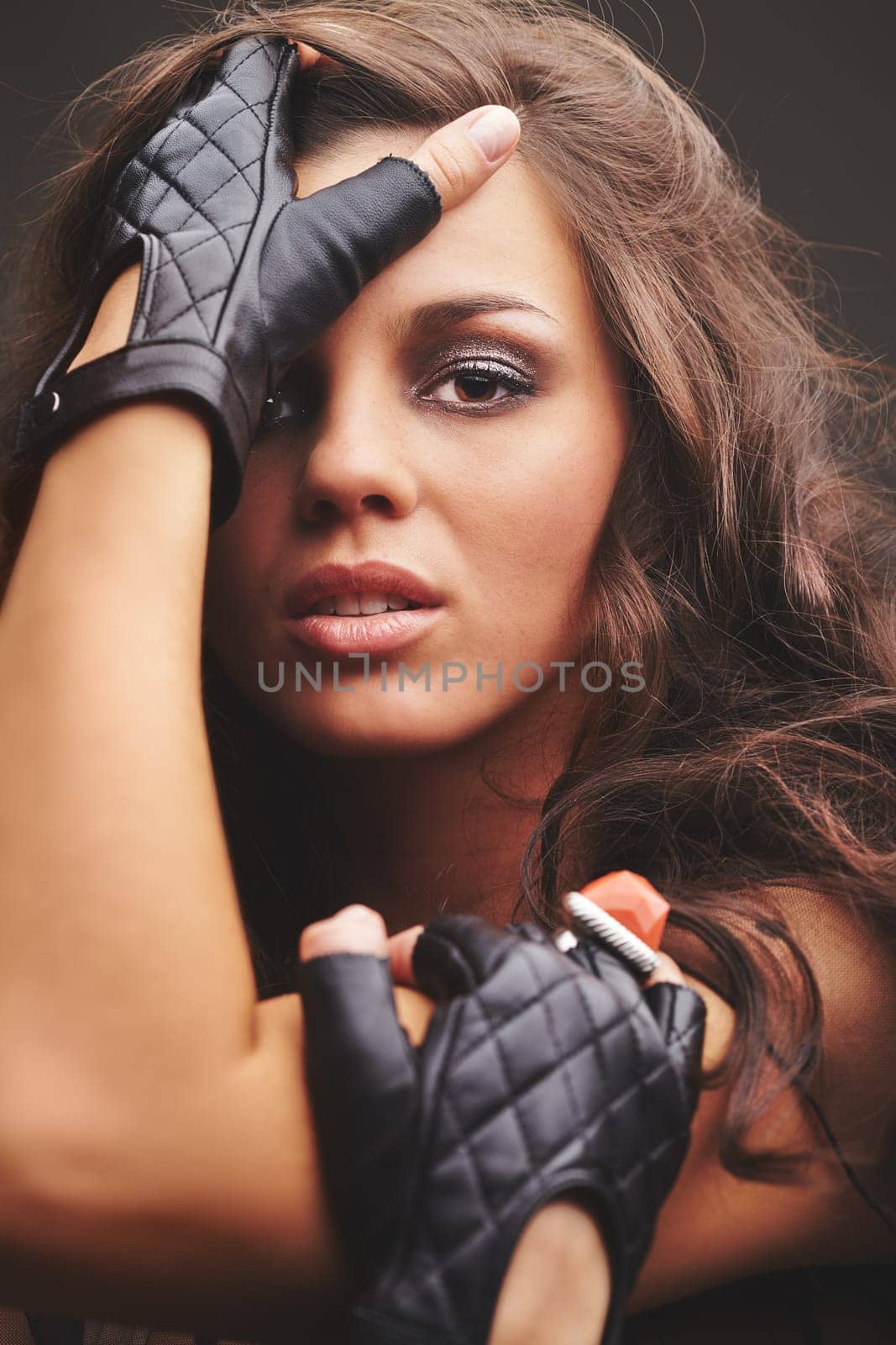Pretty glam rock girl in black leather gloves looking at camera