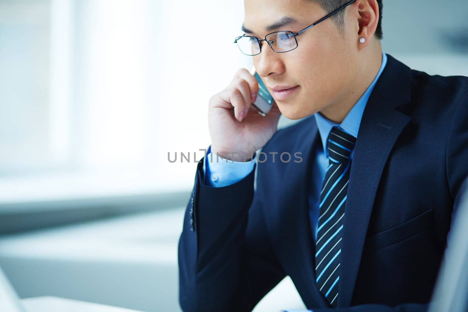 Young Asian businessman in eyeglasses speaking on the phone