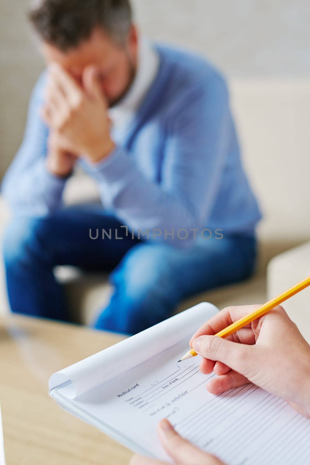 Hands of psychiatrist filling in medical document in front of stressed patient
