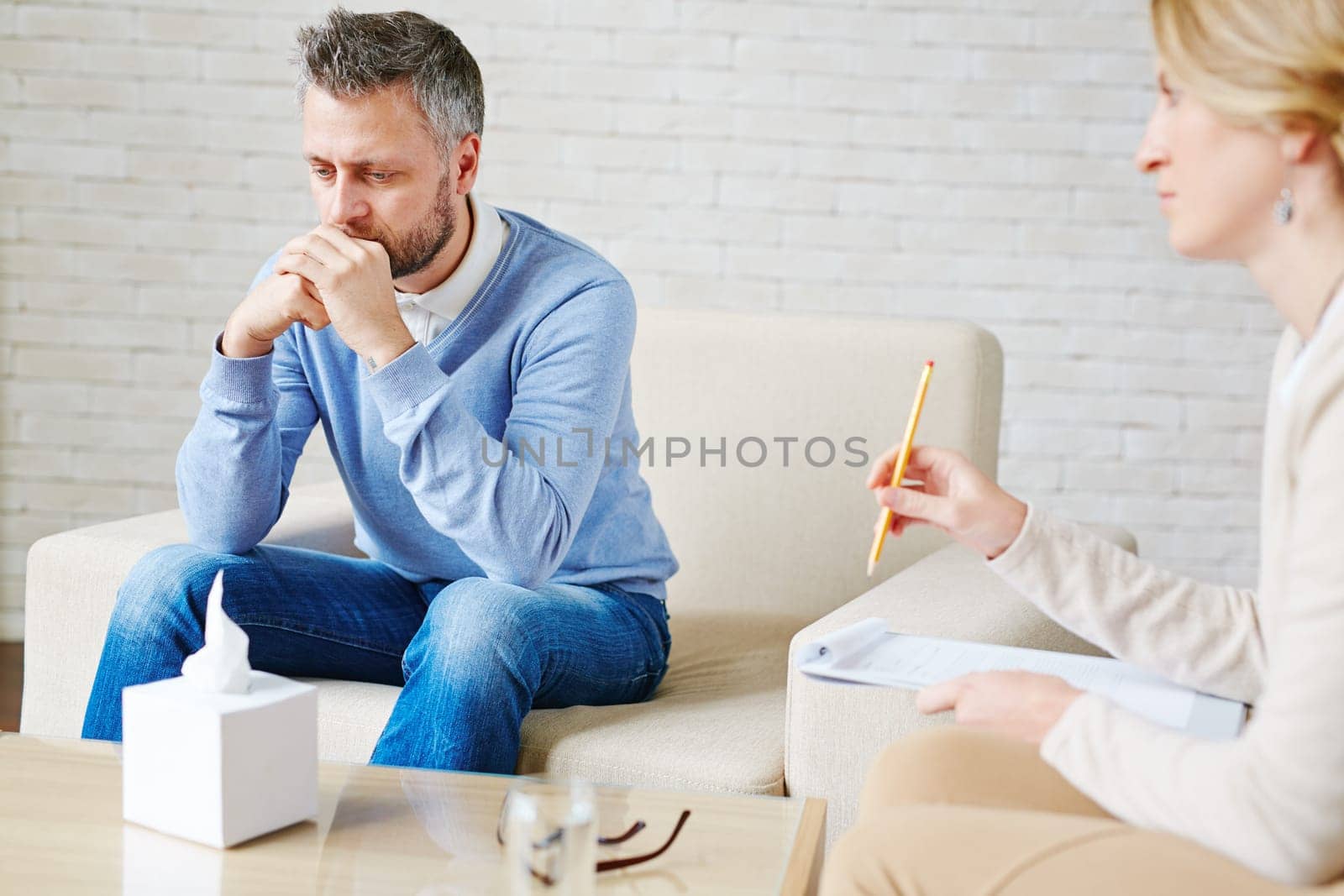 Sad man sitting by his psychologist