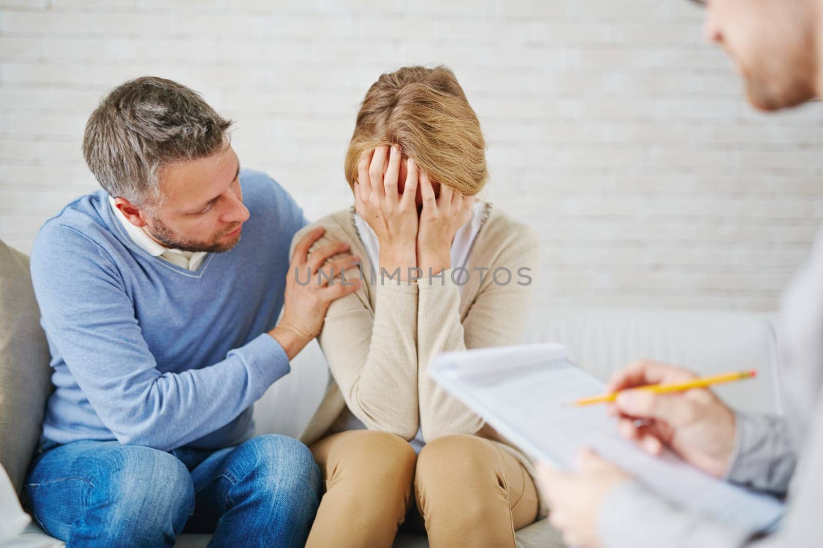 Anxious man reassuring his wife while visiting psychologist