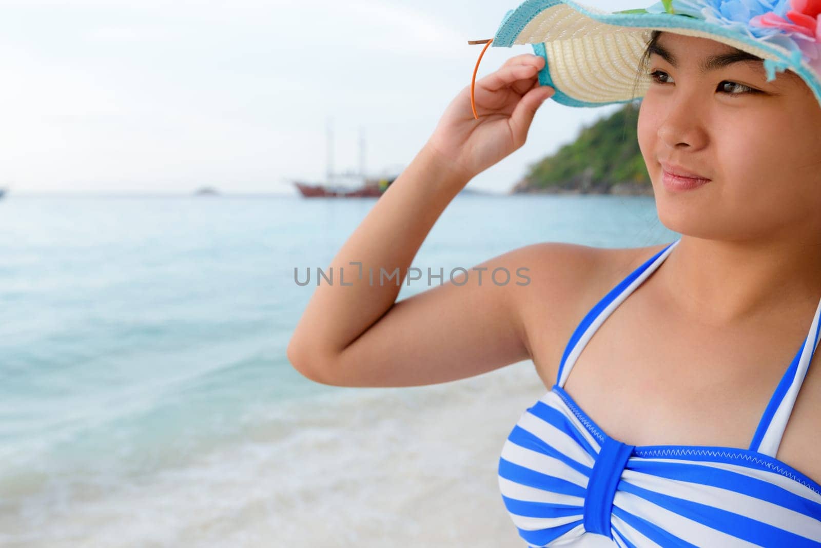 Half portrait teenage girls in a blue swimsuit looking beautiful nature of sea during sunrise with happiness on beach at Koh Miang Island, Similan National Park, Phang Nga, Thailand