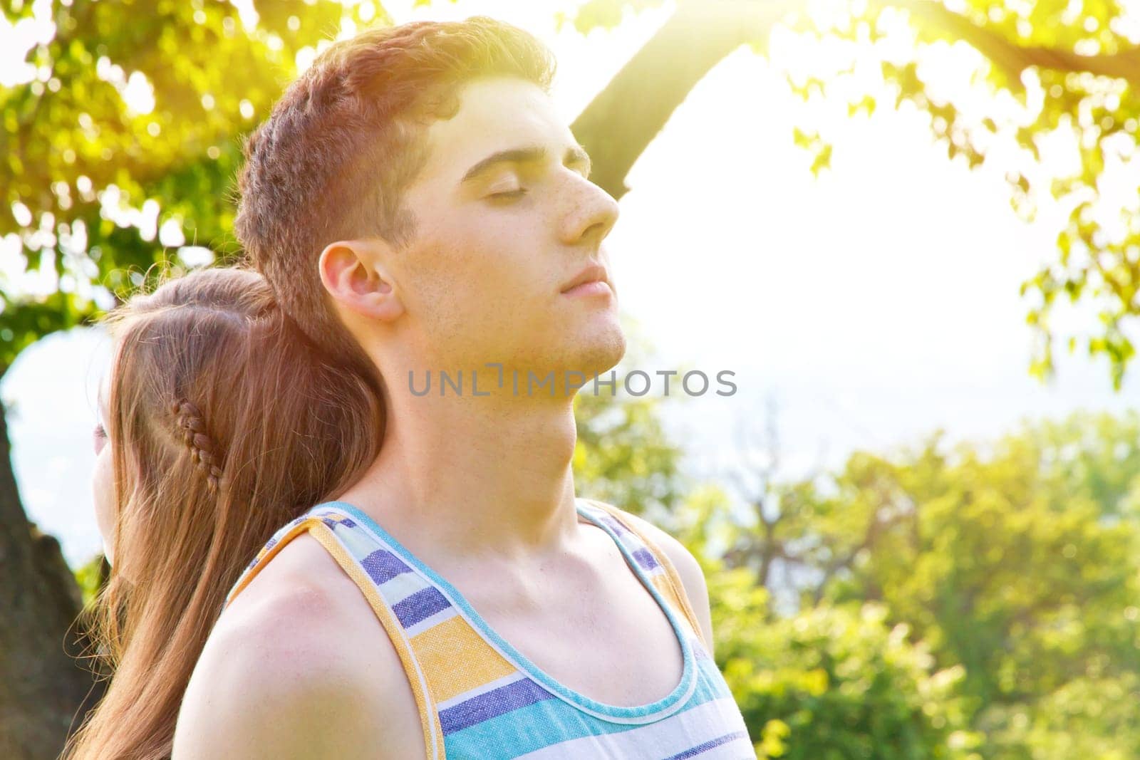 Young couple with closed eyes on a sunny day in the forest