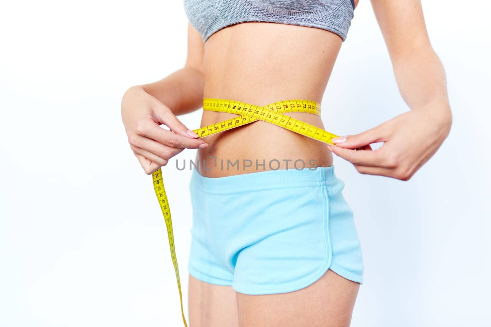Waist of slim female being measured with tape