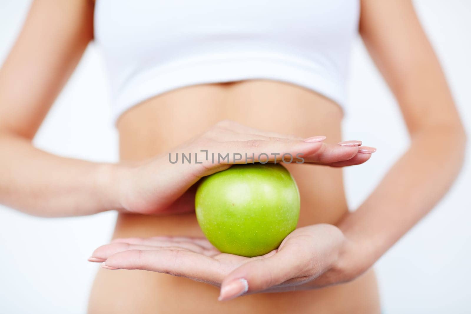 Slim female holding green apple between her palms