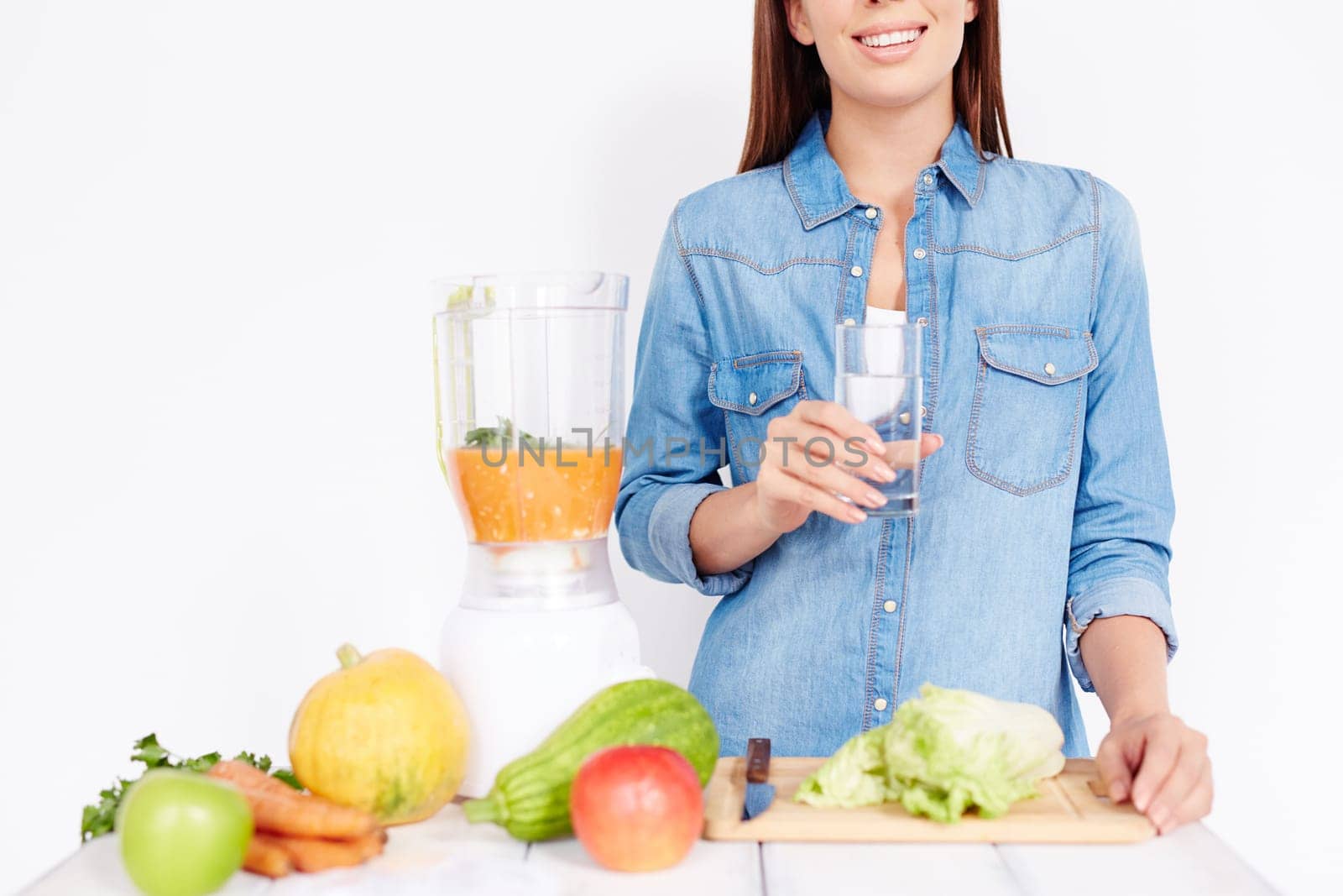 Young female with glass of water cooking breakfast from vegetables