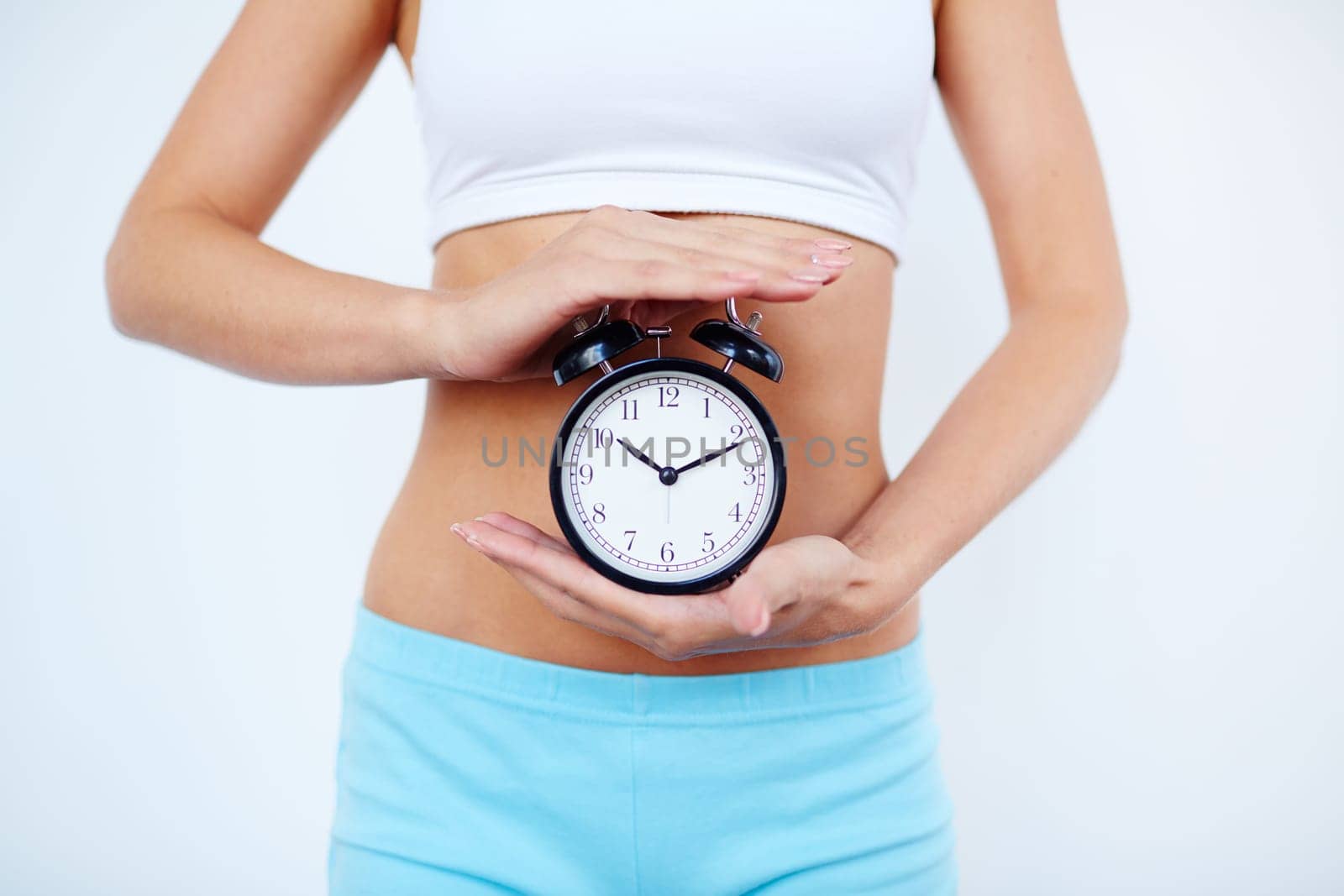 Slender female holding alarm clock between her palms