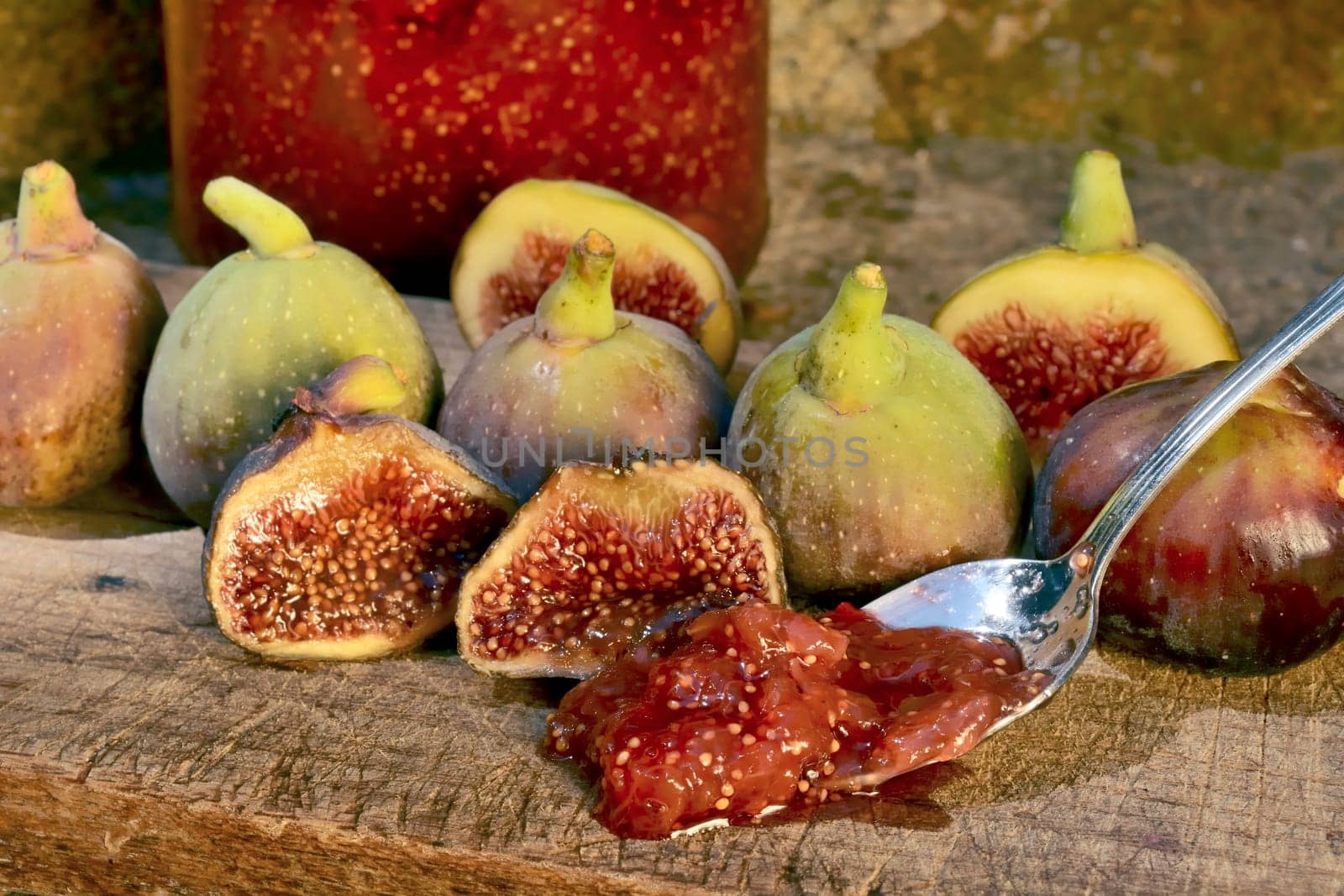 Composition of fig fruits on a wooden board and rocks in the background.