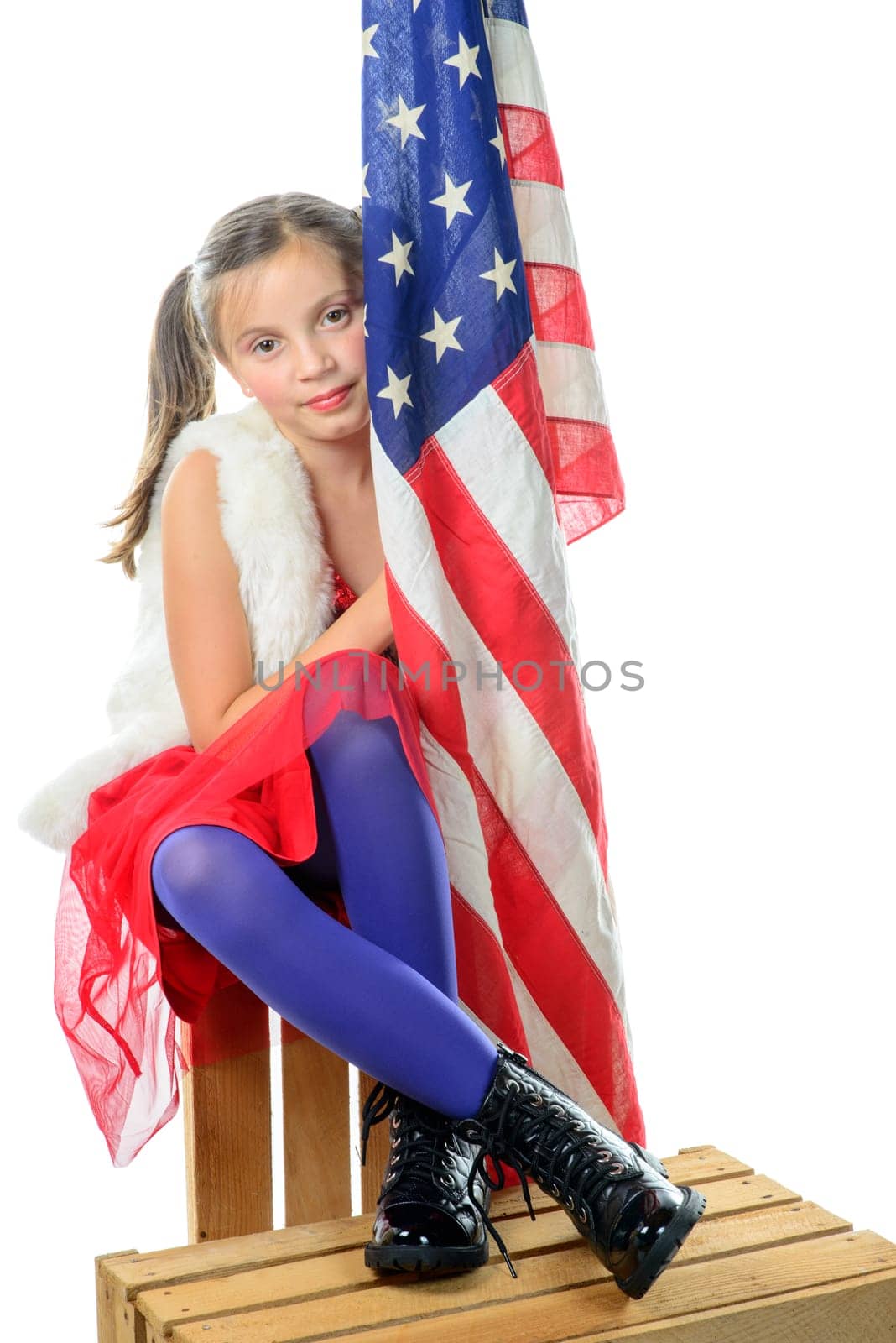 a pretty little girl sitting on a box with a american flag on the white background