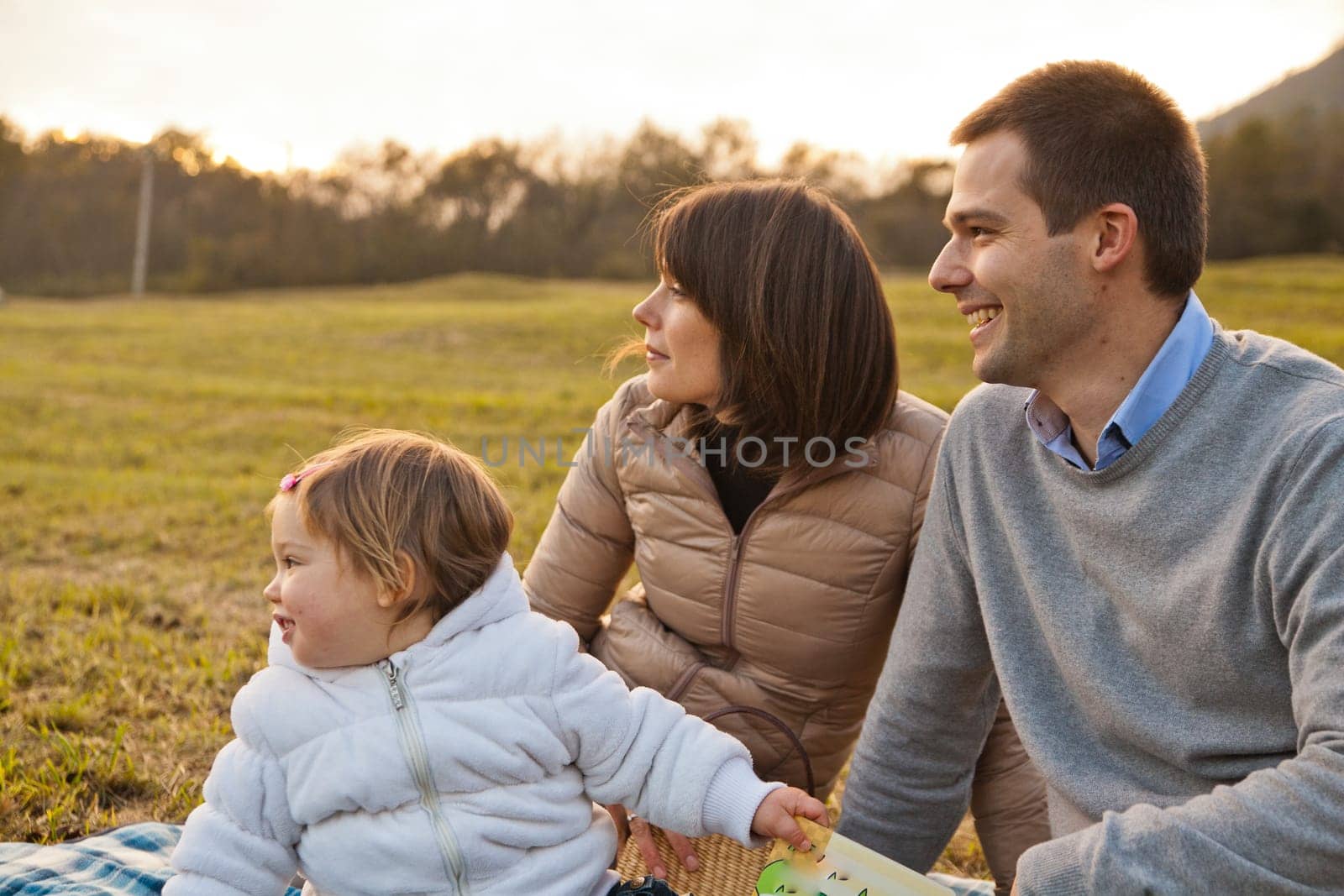 Mother Father and their little baby having happy times together in autumn outdoor in the green wood and grass