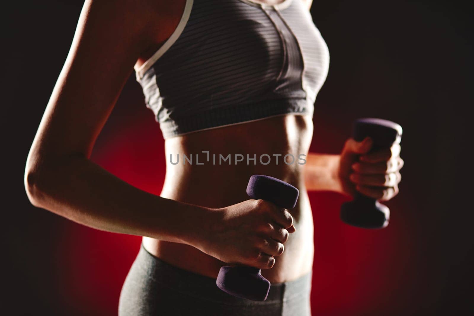 Female torso in activewear during exercise with dumbbells