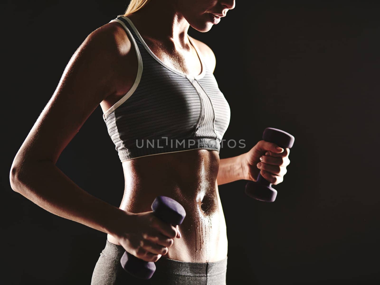 Young female training with dumbbells in isolation