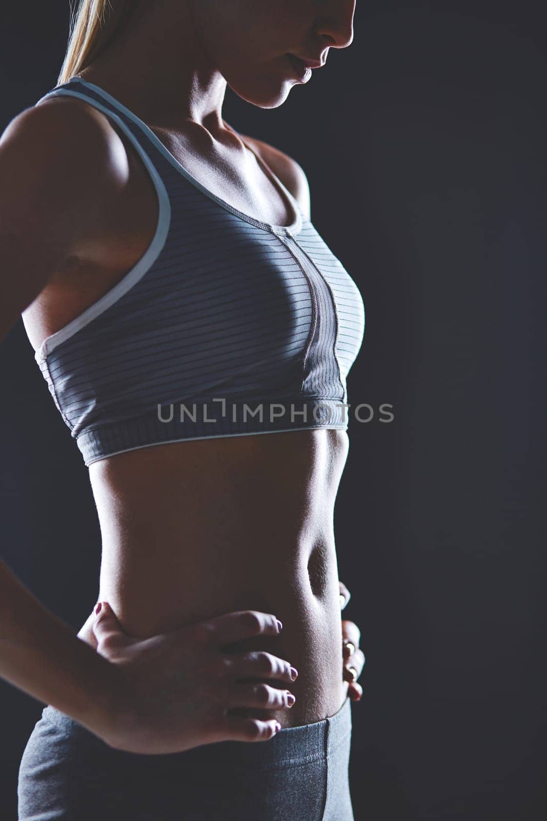 Body of slim female in activewear keeping her hands on waist