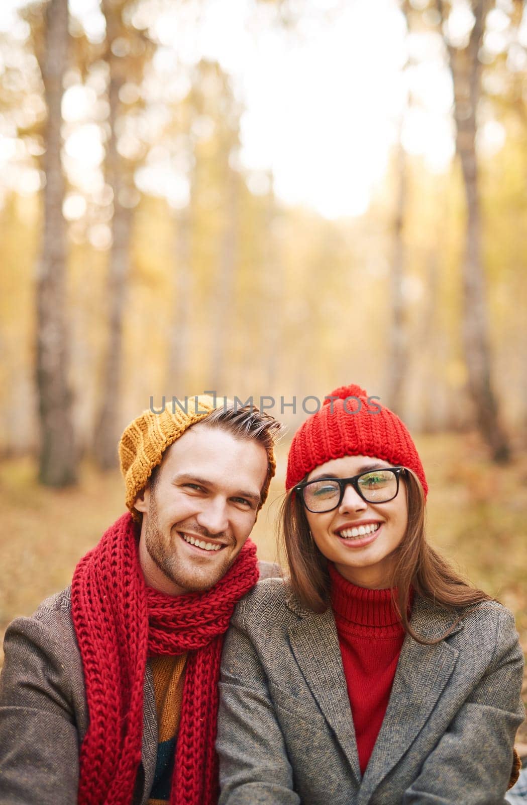 Cheerful dates in warm stylish clothes looking at camera with smiles