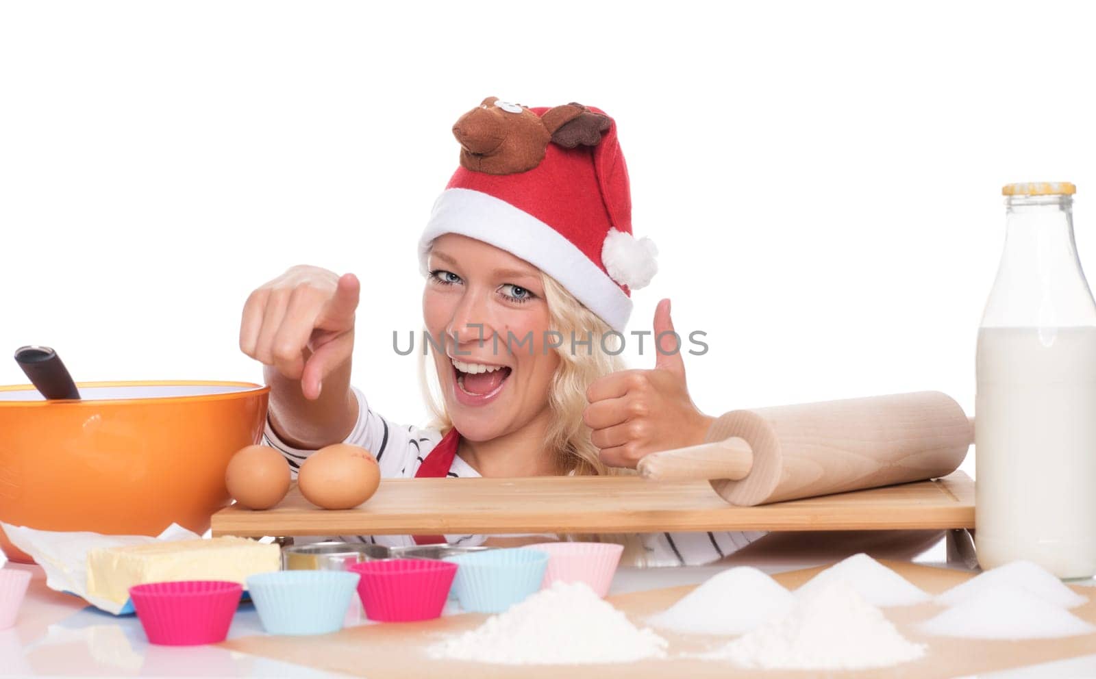 Christmas woman sits in front of baking utensils and shows up her thumbs up